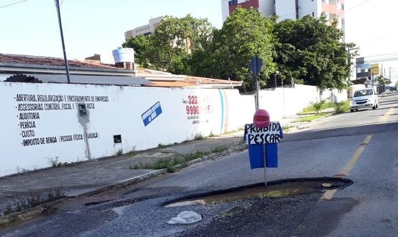 'Proibido pescar': moradores protestam por falta de solução em cratera aberta no meio da rua