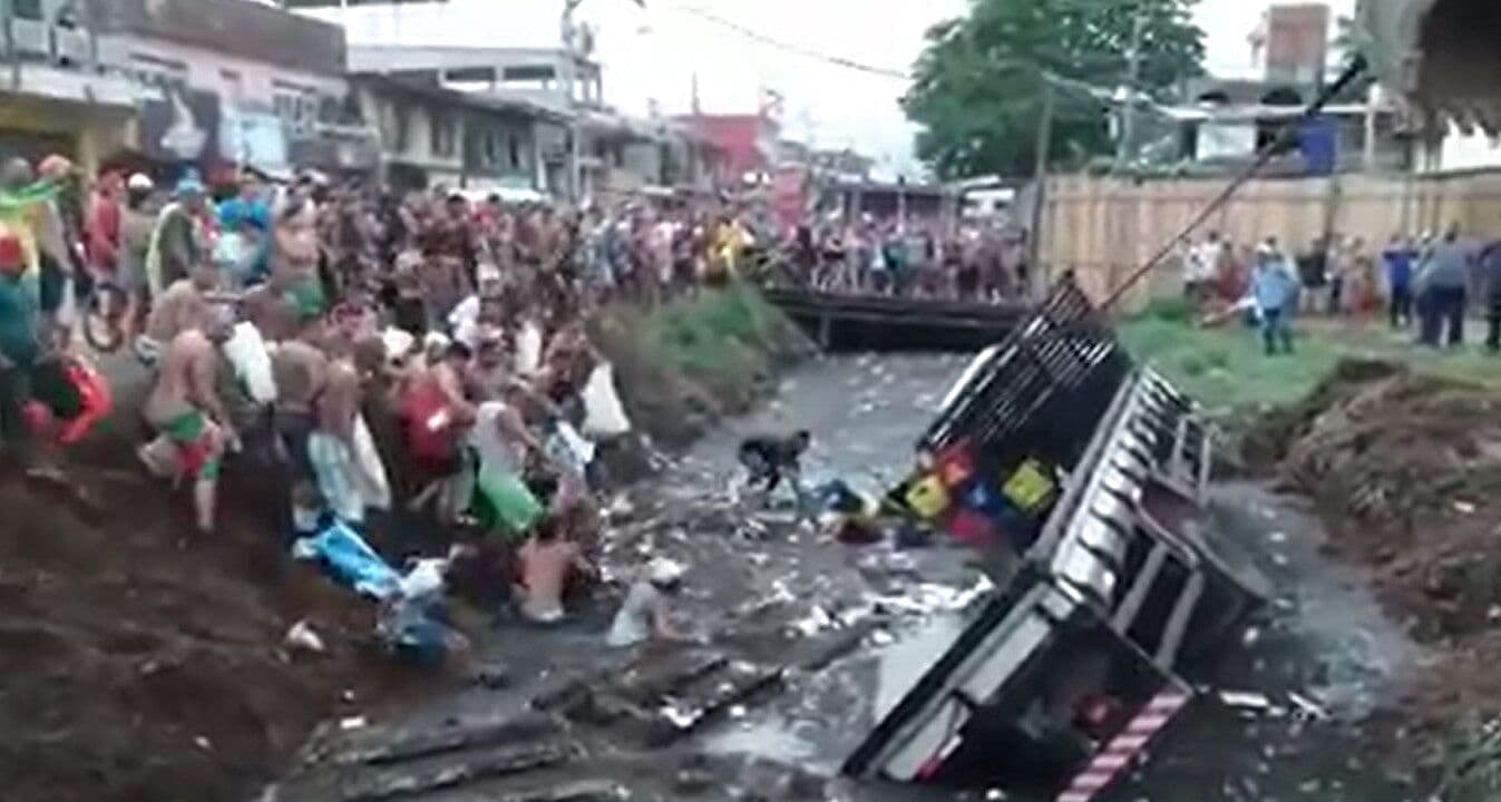 Caminhão de cervejas tomba e pessoas encaram lama para saquear carga