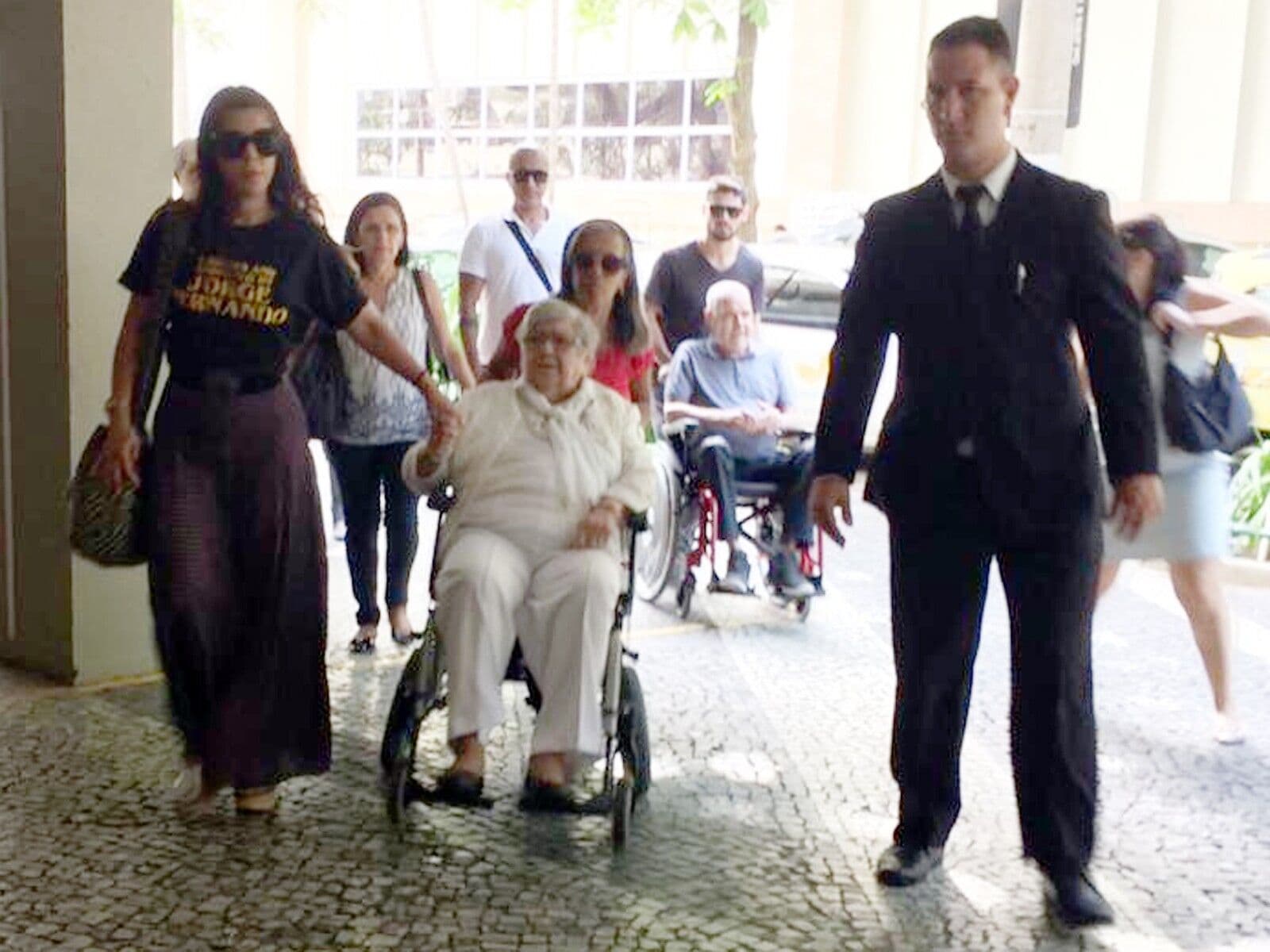 Aos 95 anos, mãe de Jorge Fernando, Hilda Rebello chega de cadeira de rodas ao velório do filho